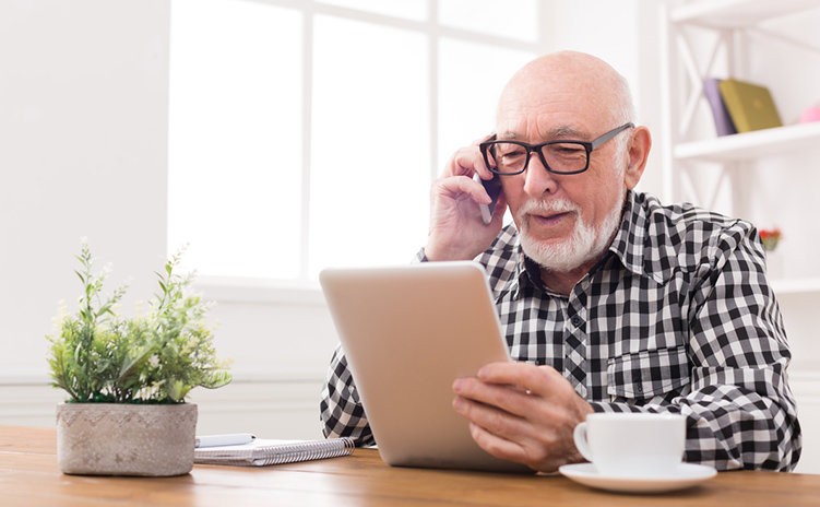 Elderly man using tablet and smartphone, representing accessibility in digital pharmacy services